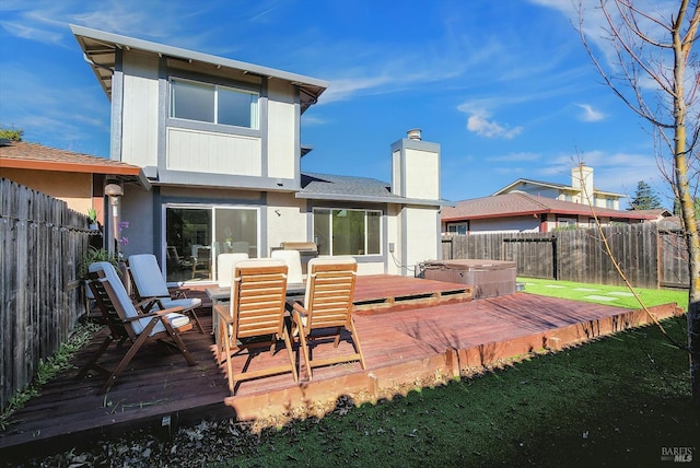 back of house featuring a wooden deck and a hot tub