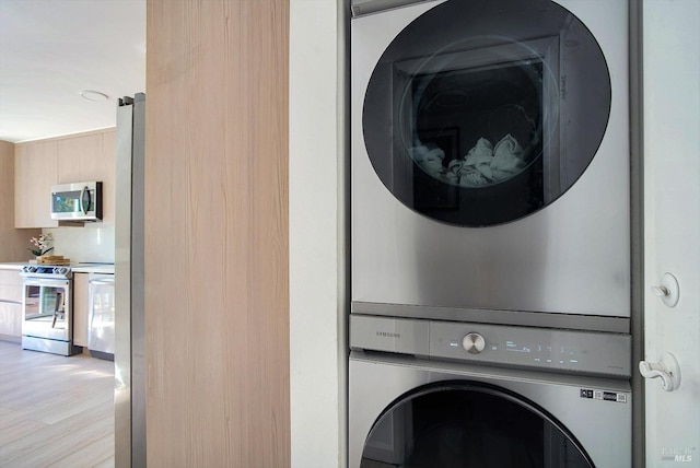 clothes washing area with stacked washer / drying machine and light hardwood / wood-style floors