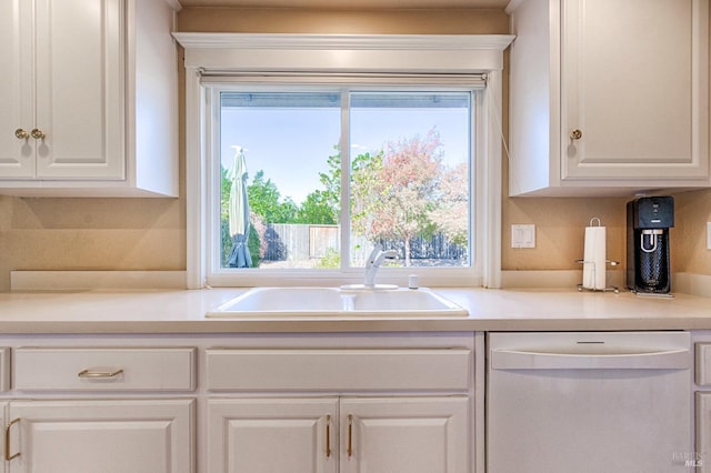 kitchen featuring light countertops, white cabinetry, white dishwasher, and a sink