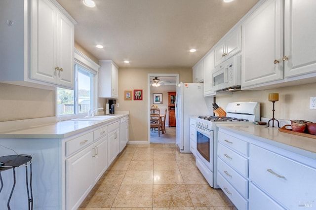 kitchen featuring light countertops, white appliances, white cabinetry, and a sink