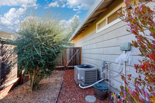 view of side of home featuring a gate, fence, and cooling unit