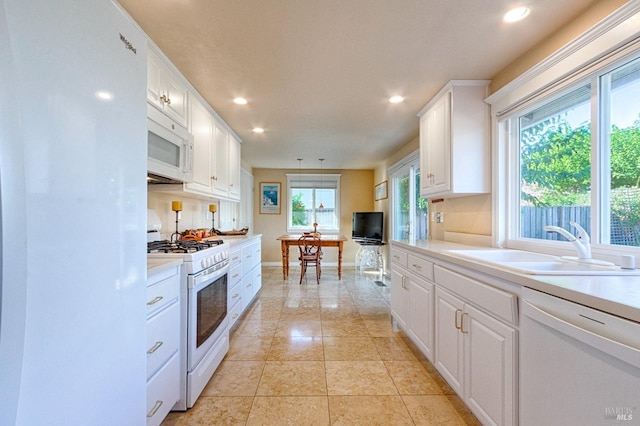 kitchen with white appliances, white cabinets, light countertops, a sink, and recessed lighting