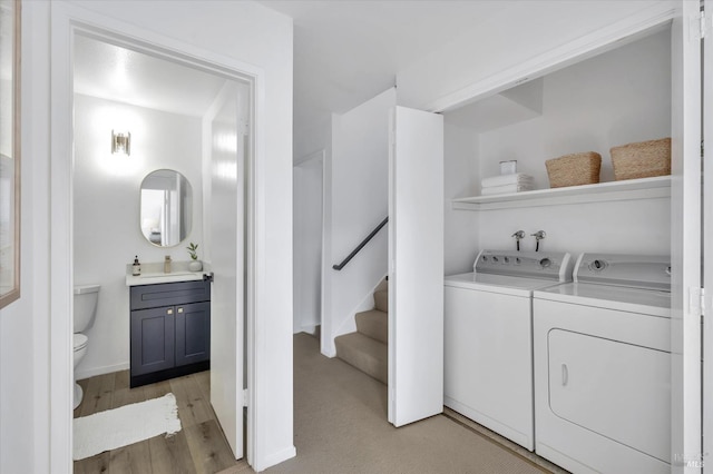 laundry area with washing machine and clothes dryer, sink, and light wood-type flooring