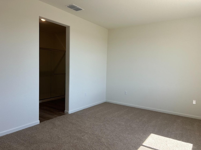 spare room featuring dark colored carpet