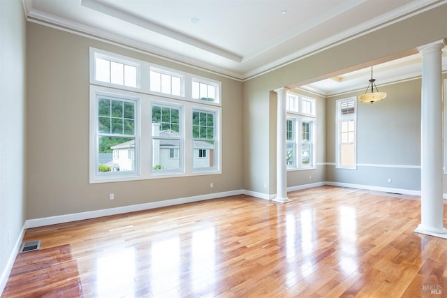 unfurnished room featuring decorative columns, light hardwood / wood-style flooring, a tray ceiling, and ornamental molding