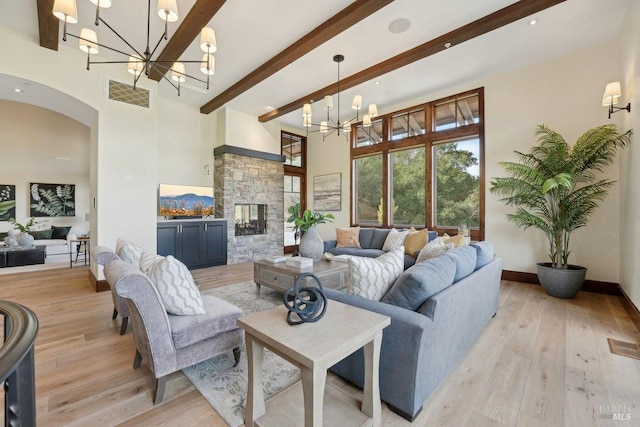 living area featuring a chandelier, light wood-style flooring, beamed ceiling, and visible vents