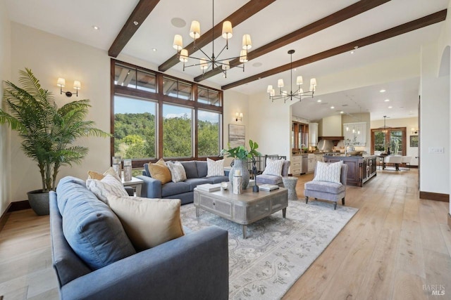 living area featuring a chandelier, light wood-style floors, a healthy amount of sunlight, and beamed ceiling