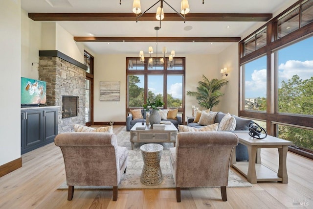 living area with light wood-style floors, a fireplace, a wealth of natural light, and a notable chandelier