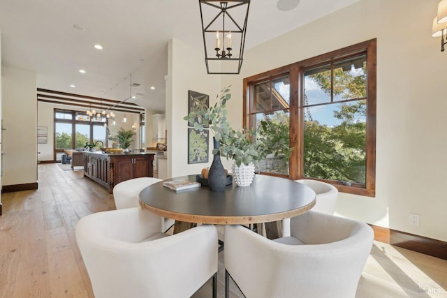 dining area with light wood-type flooring, baseboards, an inviting chandelier, and recessed lighting