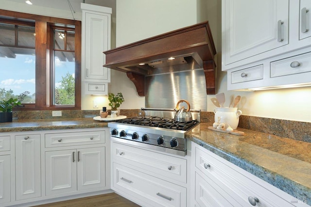 kitchen with stainless steel gas stovetop, premium range hood, and white cabinets