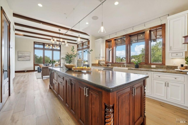 kitchen with a healthy amount of sunlight, a center island, light wood-type flooring, white cabinetry, and pendant lighting