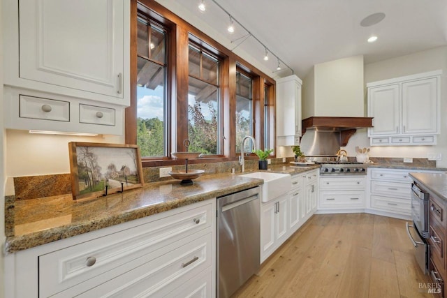 kitchen featuring premium range hood, white cabinetry, appliances with stainless steel finishes, and a sink