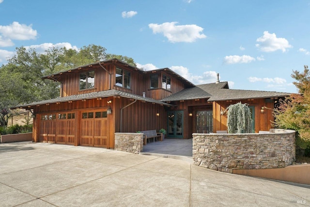 view of front of home featuring a garage, concrete driveway, and roof with shingles