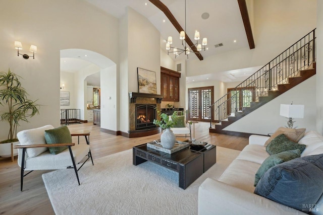 living room featuring light wood-style floors, a lit fireplace, stairs, and visible vents