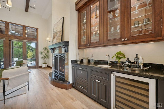 bar featuring beverage cooler, visible vents, a sink, light wood-type flooring, and indoor wet bar