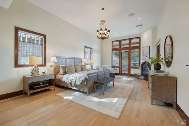 bedroom featuring light wood-style flooring, a high ceiling, baseboards, and a chandelier