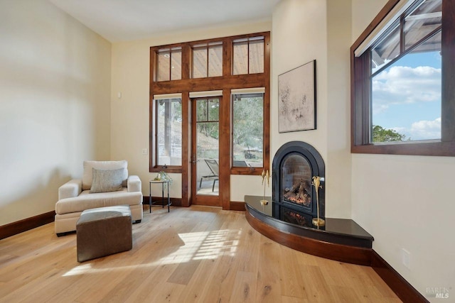 sitting room featuring baseboards, hardwood / wood-style floors, and a glass covered fireplace