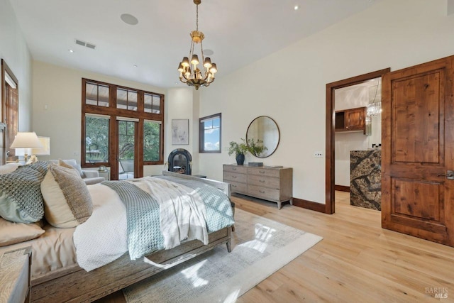 bedroom with french doors, a notable chandelier, light wood finished floors, visible vents, and baseboards