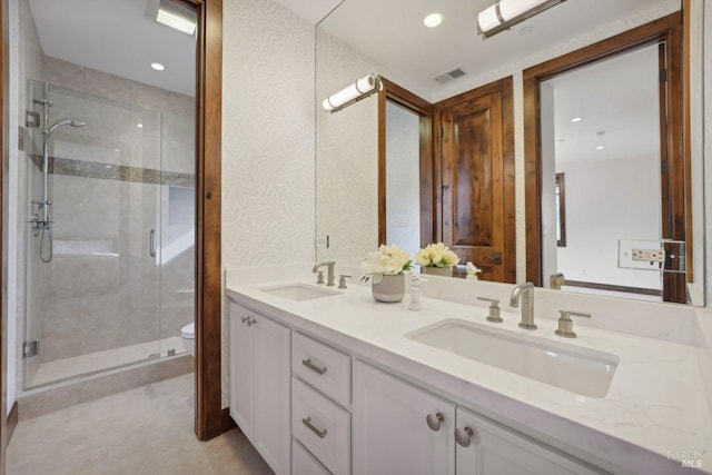 bathroom featuring a sink, a shower stall, toilet, and double vanity