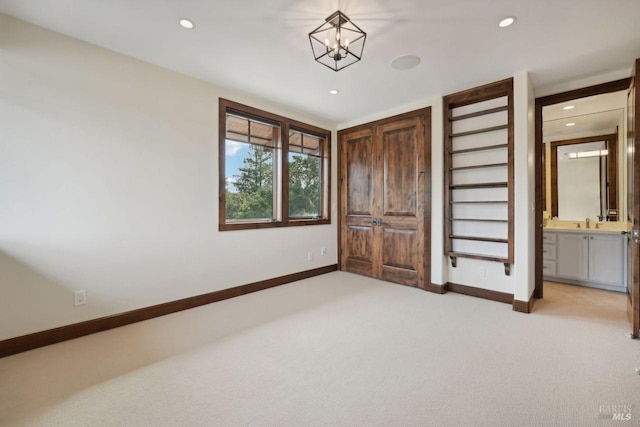 unfurnished bedroom featuring light carpet, baseboards, ensuite bathroom, and recessed lighting