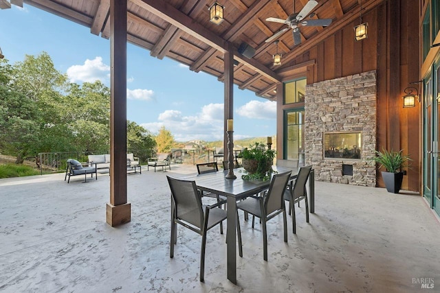 view of patio featuring a ceiling fan, an outdoor stone fireplace, and fence