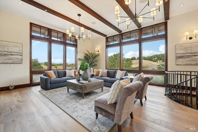 living room with light wood-type flooring, a wealth of natural light, a notable chandelier, and beamed ceiling