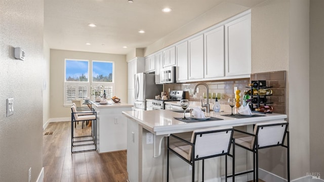 kitchen featuring white cabinetry, a center island, sink, a breakfast bar area, and appliances with stainless steel finishes