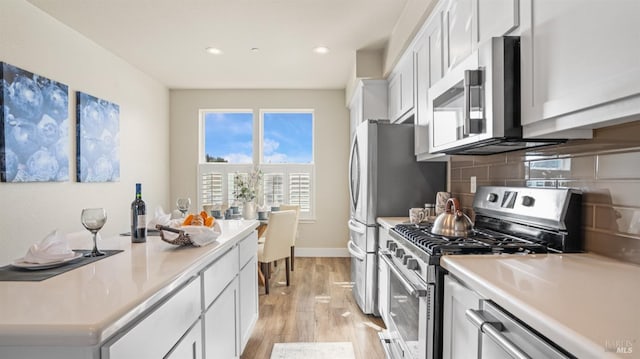 kitchen featuring tasteful backsplash, white cabinetry, stainless steel appliances, and light wood-type flooring