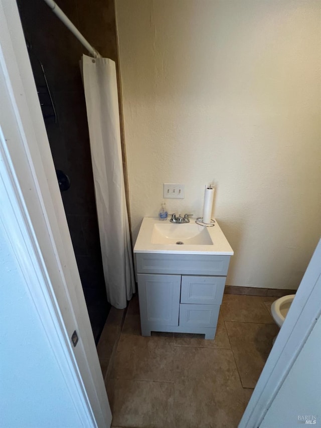 bathroom with vanity, toilet, walk in shower, and tile patterned flooring