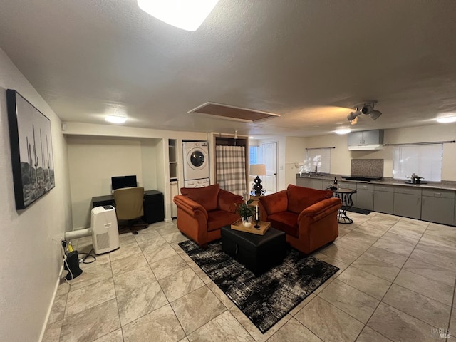 living room featuring sink, stacked washer / dryer, and a textured ceiling