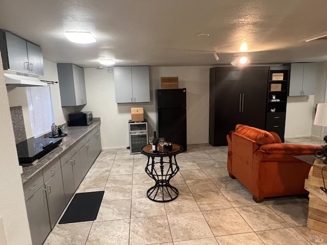 kitchen with black refrigerator, light tile patterned flooring, a textured ceiling, and gray cabinets