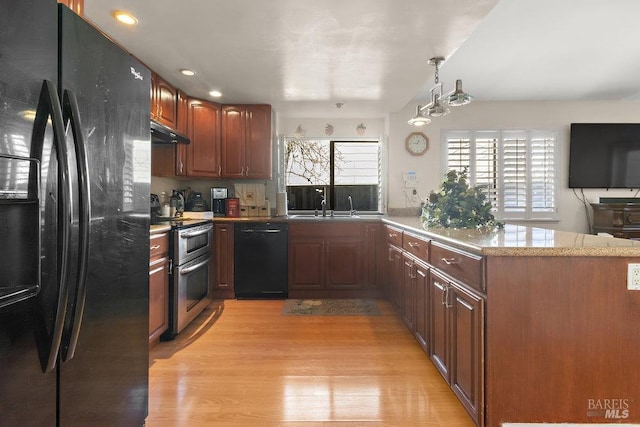 kitchen with kitchen peninsula, light wood-type flooring, light stone counters, sink, and black appliances