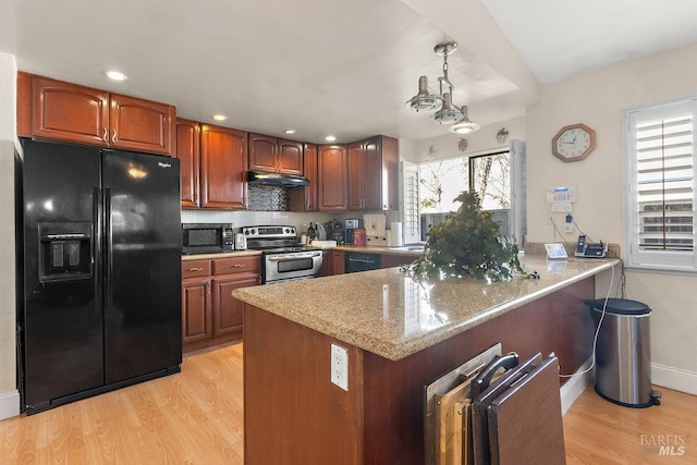 kitchen featuring light stone countertops, hanging light fixtures, kitchen peninsula, black appliances, and light wood-type flooring