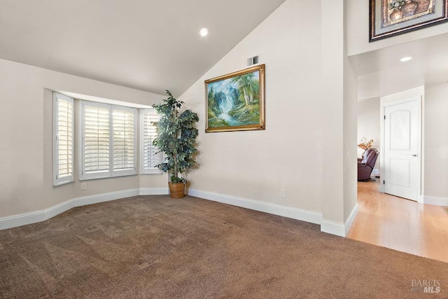 spare room with light carpet and high vaulted ceiling