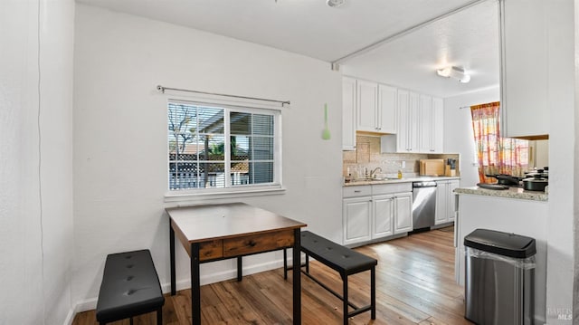 kitchen featuring backsplash, sink, light hardwood / wood-style flooring, dishwasher, and white cabinets