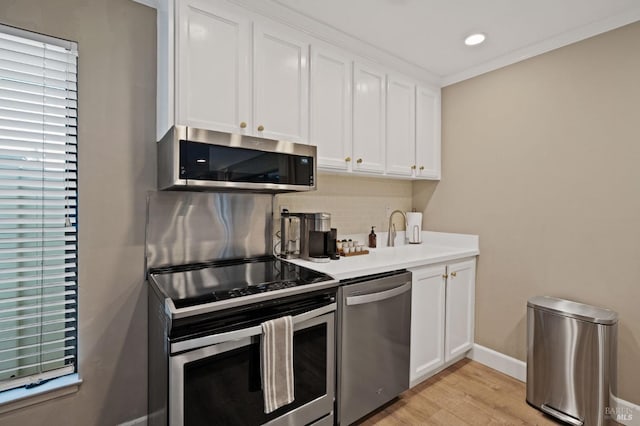 kitchen featuring tasteful backsplash, white cabinets, appliances with stainless steel finishes, light countertops, and a sink