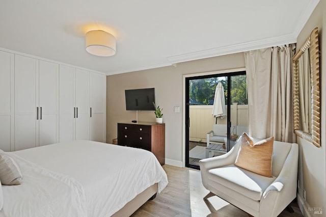 bedroom with access to exterior, baseboards, light wood finished floors, and crown molding