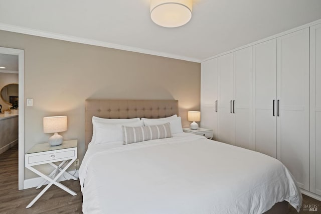 bedroom featuring baseboards, a closet, wood finished floors, and crown molding