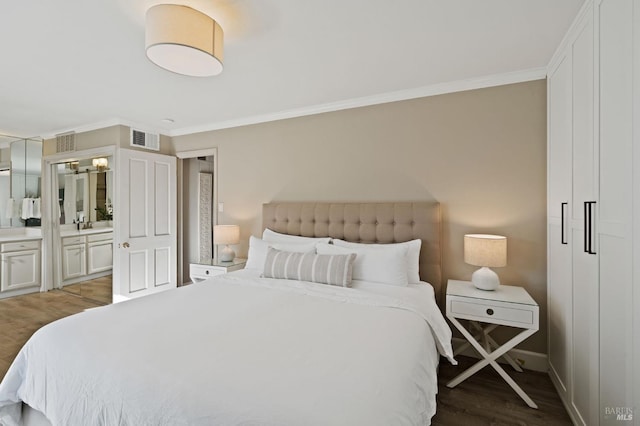 bedroom featuring ensuite bath, wood finished floors, visible vents, and crown molding