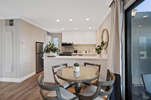 dining area with baseboards, visible vents, ornamental molding, and wood finished floors