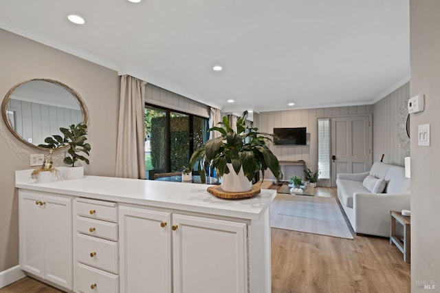 kitchen with crown molding, light wood finished floors, light countertops, open floor plan, and white cabinets