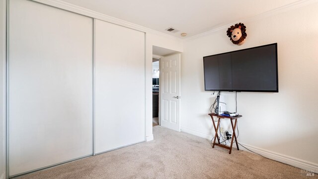 bedroom with light carpet, a closet, and ornamental molding