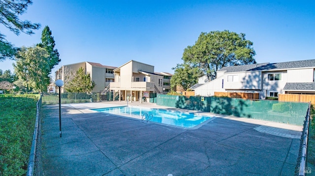 view of swimming pool with a patio area, a residential view, a fenced in pool, and fence