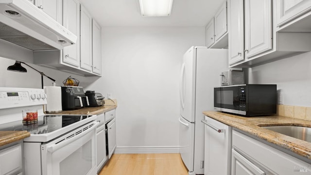 kitchen with light stone countertops, light hardwood / wood-style floors, white cabinetry, and electric stove