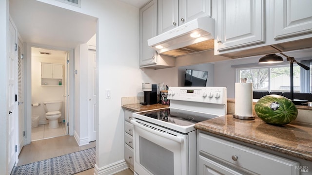 kitchen featuring baseboards, under cabinet range hood, dark stone countertops, electric range, and white cabinets
