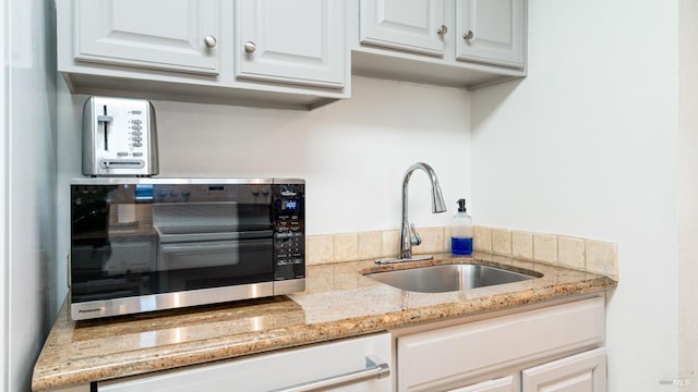 kitchen featuring a sink, light stone counters, white cabinets, white dishwasher, and a toaster
