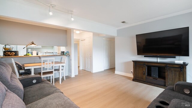 living room with ornamental molding, track lighting, and hardwood / wood-style flooring