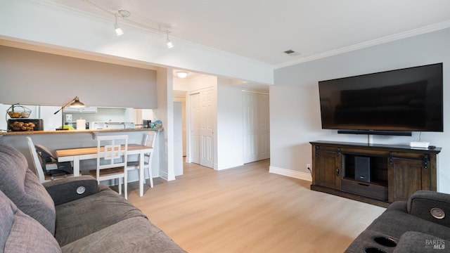 living area featuring visible vents, baseboards, wood finished floors, and crown molding