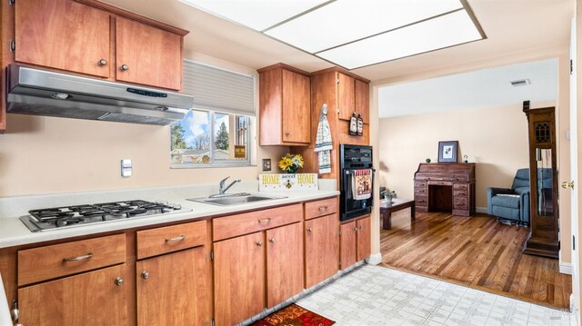 kitchen featuring light hardwood / wood-style floors, oven, stainless steel gas cooktop, and sink