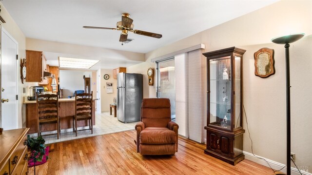 living area with ceiling fan and light wood-type flooring